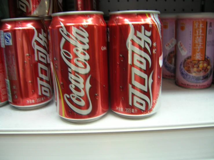 cans of coca - cola on a shelf in a supermarket