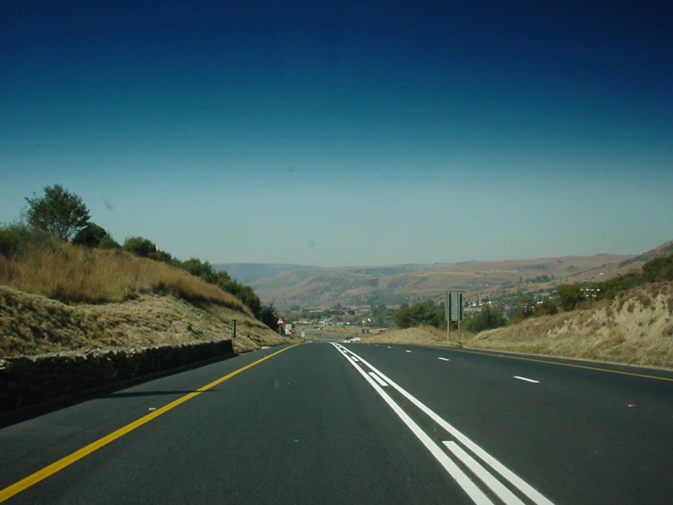 a road near mountains and hills in the distance