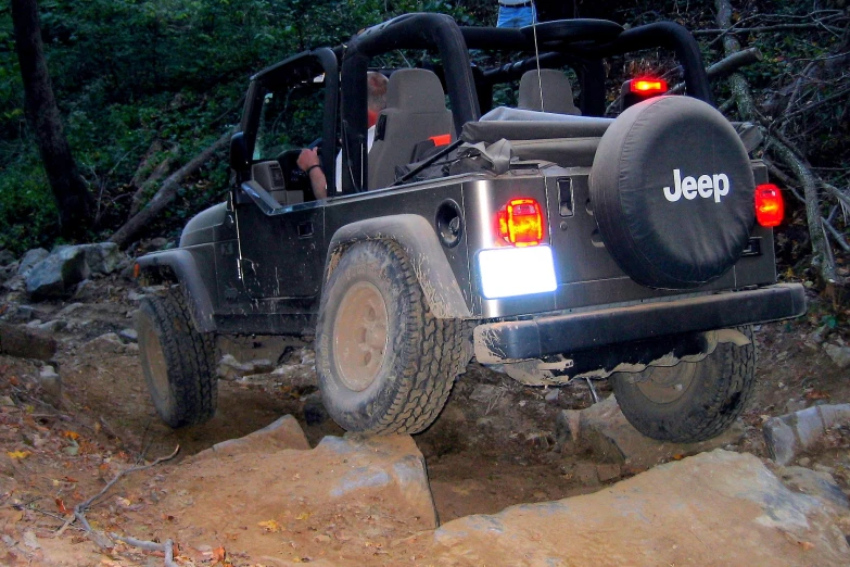 a black jeep on a rock in the woods