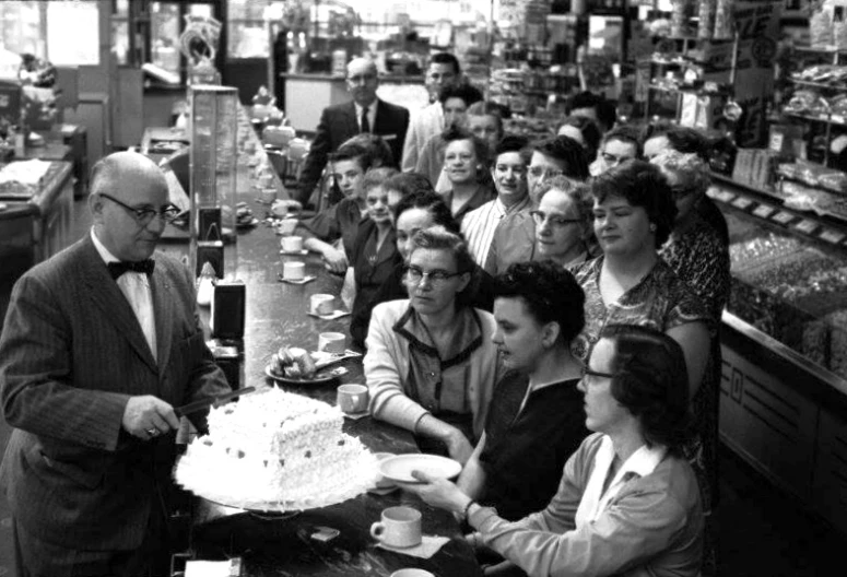 a large group of people at a store looking at a cake