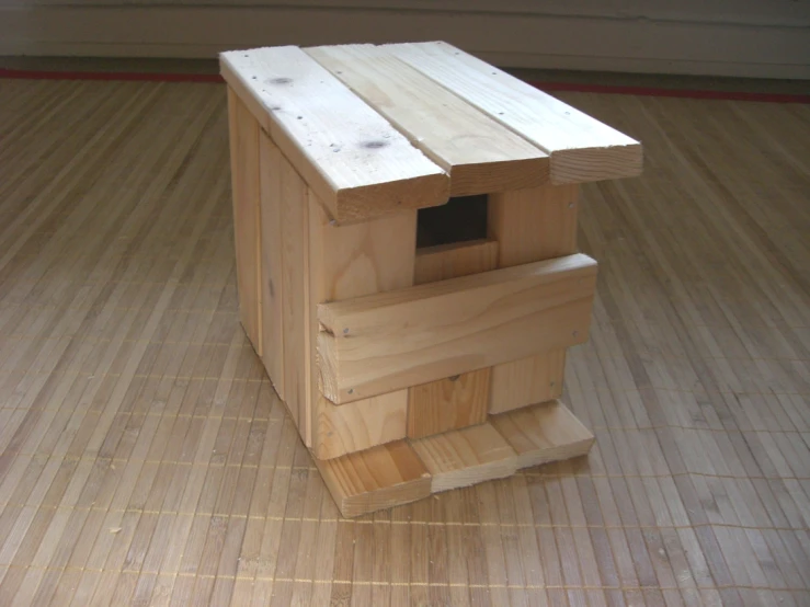 a cat house is on the floor made from wooden boards