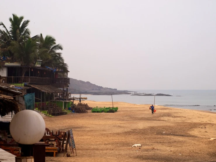 a lone man is walking down the beach next to the ocean