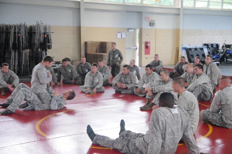 a group of military people sitting on a gym floor