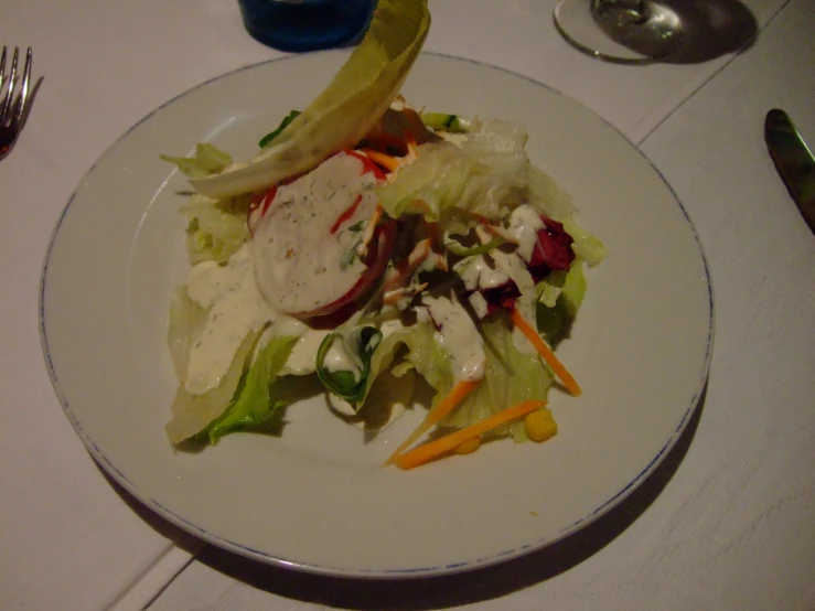 a white plate with a salad and some spoons on a table