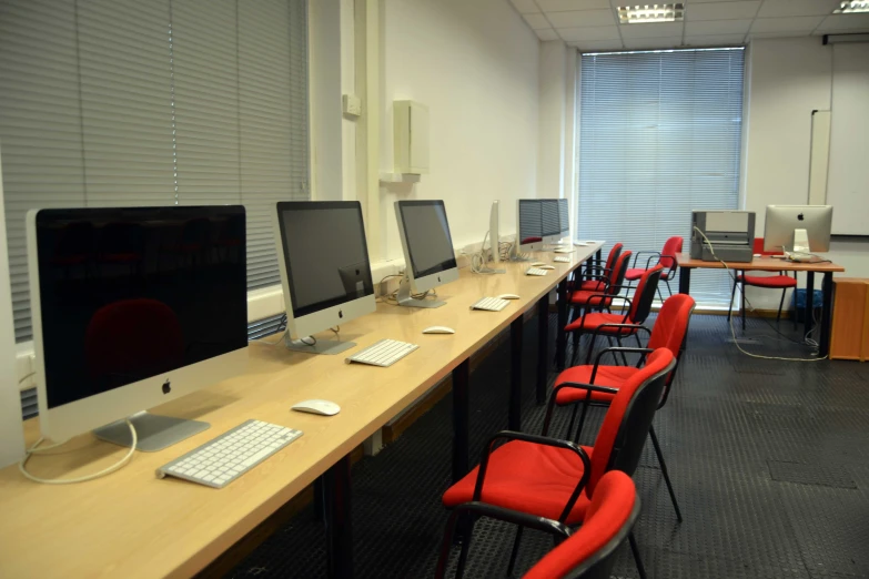 computers are lined up on the long desk