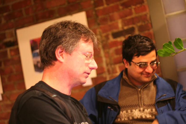 two men are looking at a cellphone that is on the ground