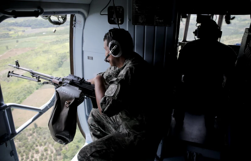 a man riding a helicopter with a gun