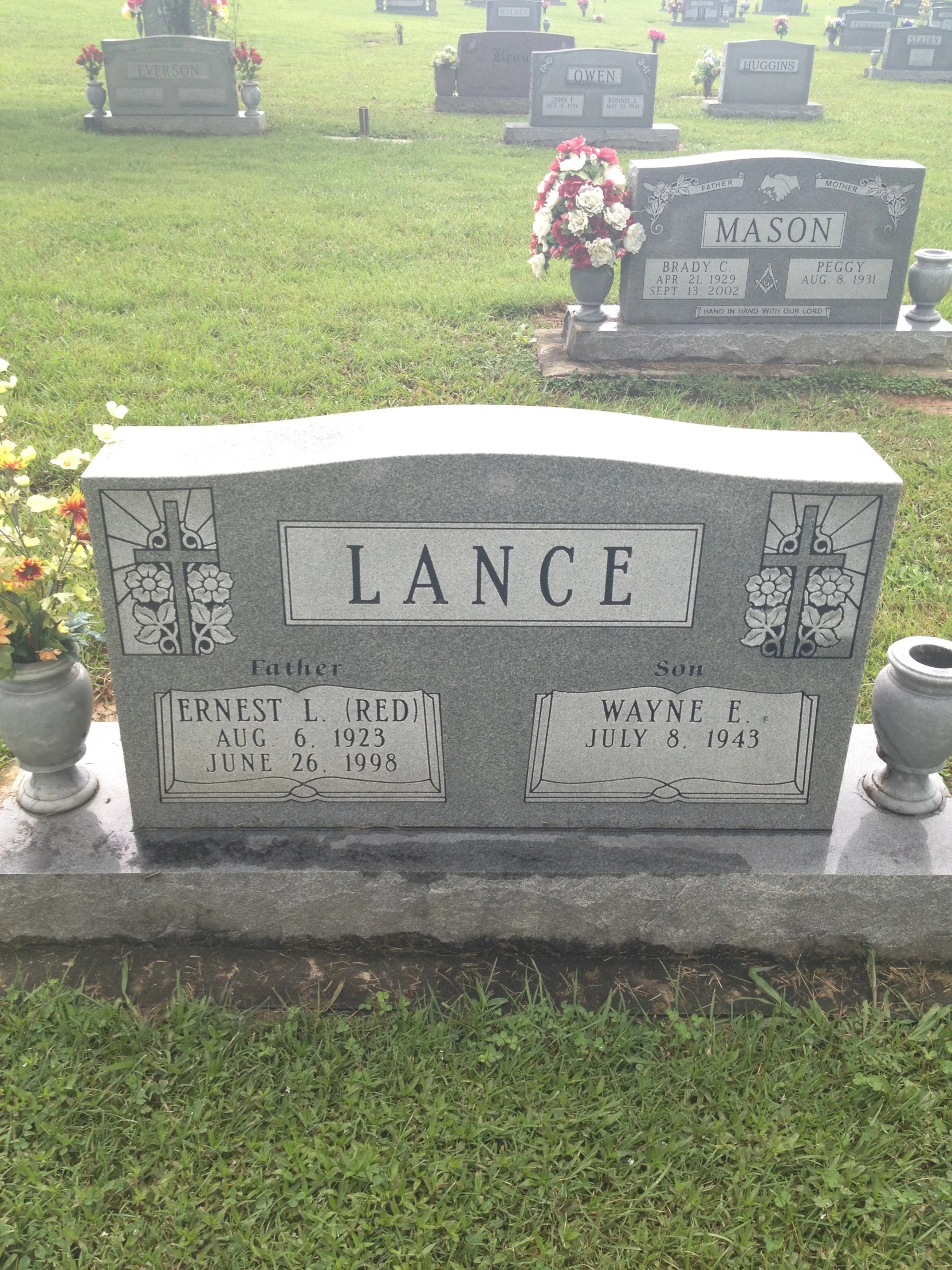 a headstone sits on a tombstone, among a grassy lawn