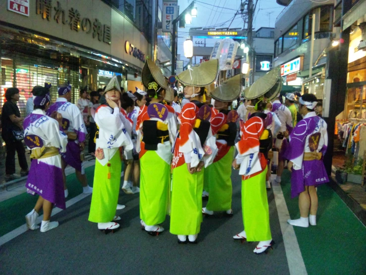 a group of asian women in brightly colored outfits on the street