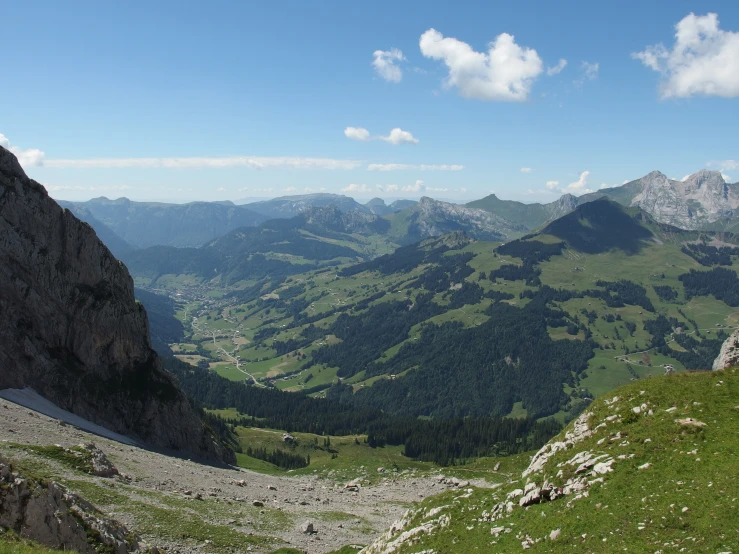 a green grassy hill in the mountains with a valley in the distance