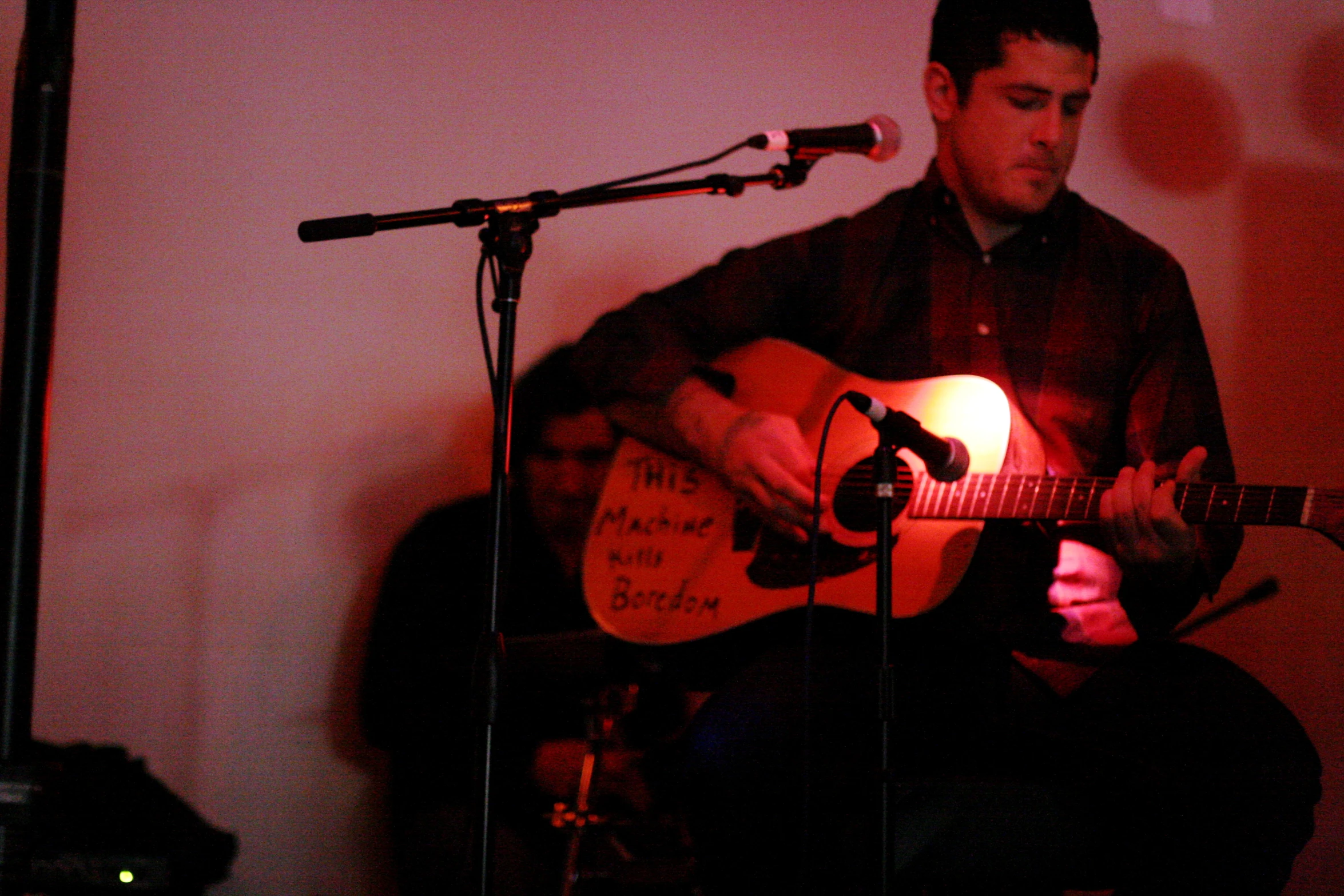 a man in the dark playing an acoustic guitar