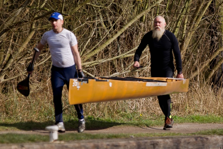 a man and a woman walking beside a yellow canoe