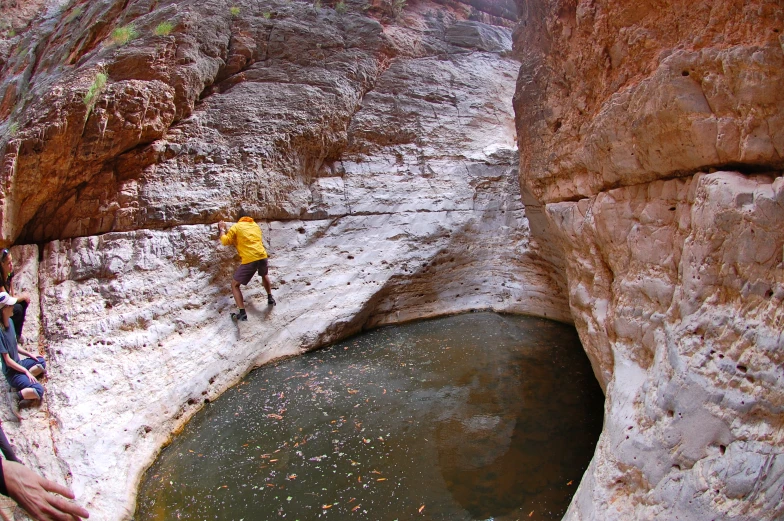 a man climbing a cliff and crossing in an artificial rock pool