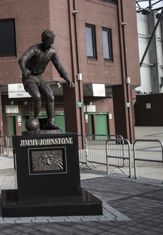 statue of a man sitting on top of a soccer ball