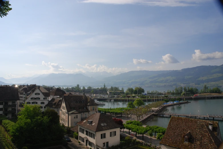 the mountains are in the distance behind houses by water