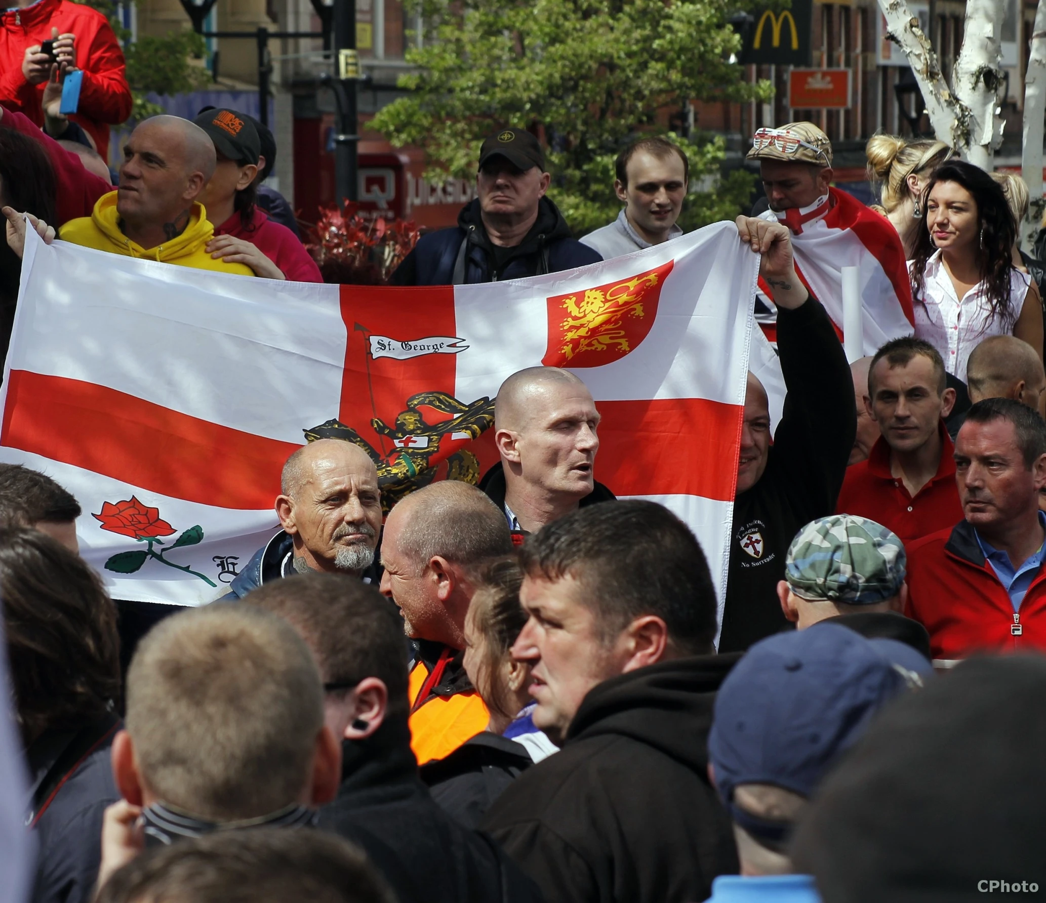 many people gather outside with a flag and banners