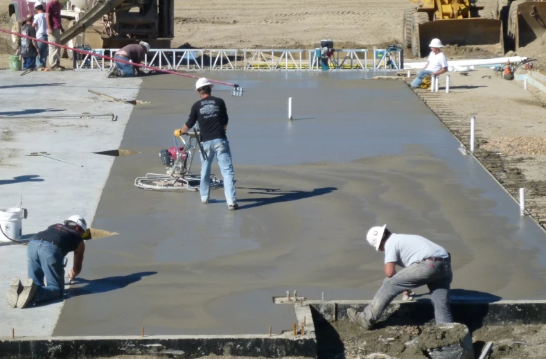 construction workers are standing around on a slab of concrete