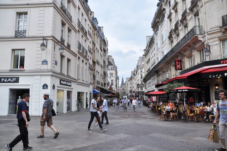 people walk down a wide street in front of some buildings