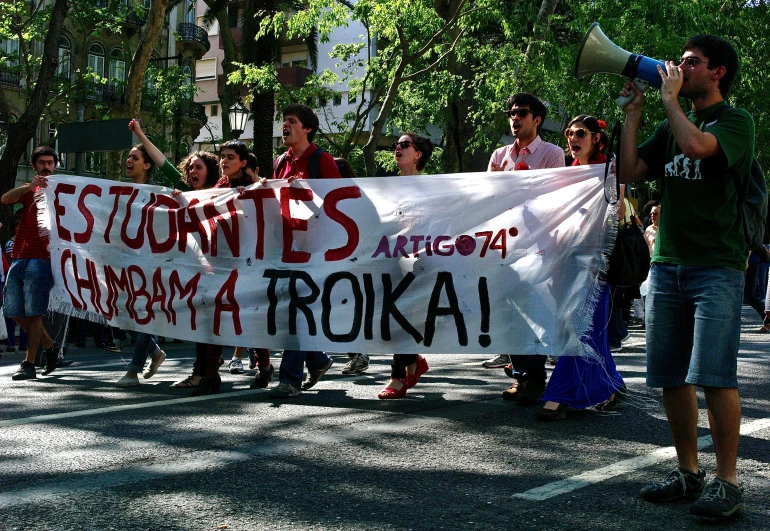 people marching in a demonstration holding up a white banner