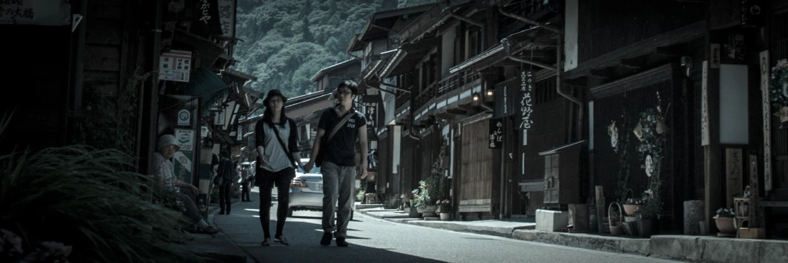 two people walk down the street of a japanese town