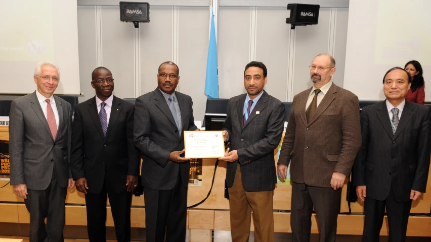 men standing side by side while one man is holding up a plaque