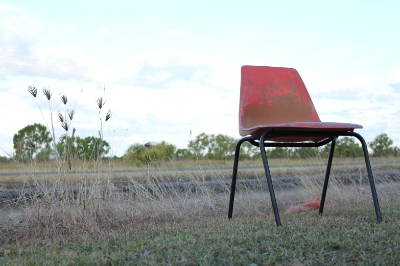 an empty chair sits on a grassy field