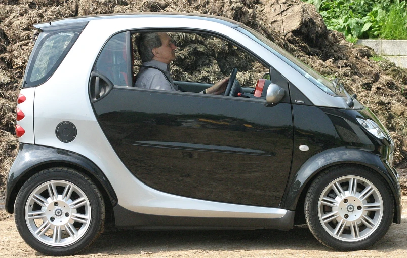 a woman driving a small car down a dirt road