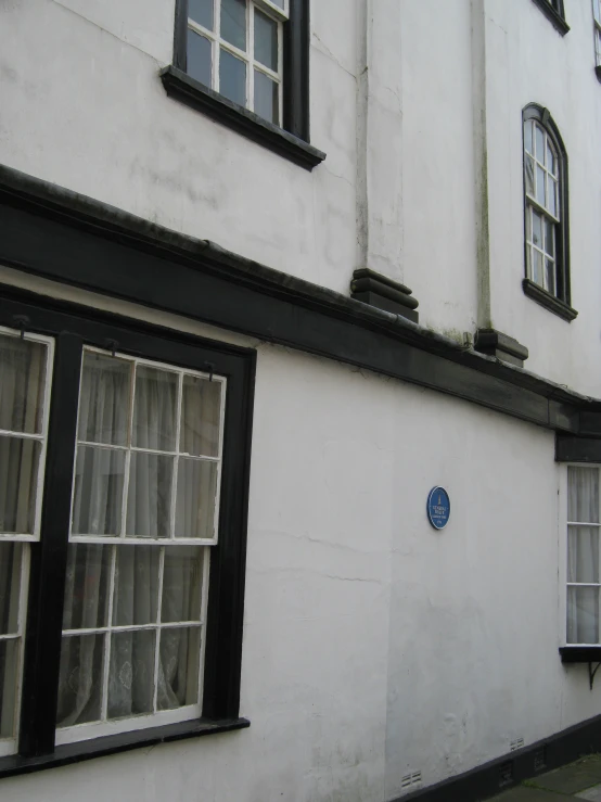 a building with two windows and a black - framed blue sign in the corner