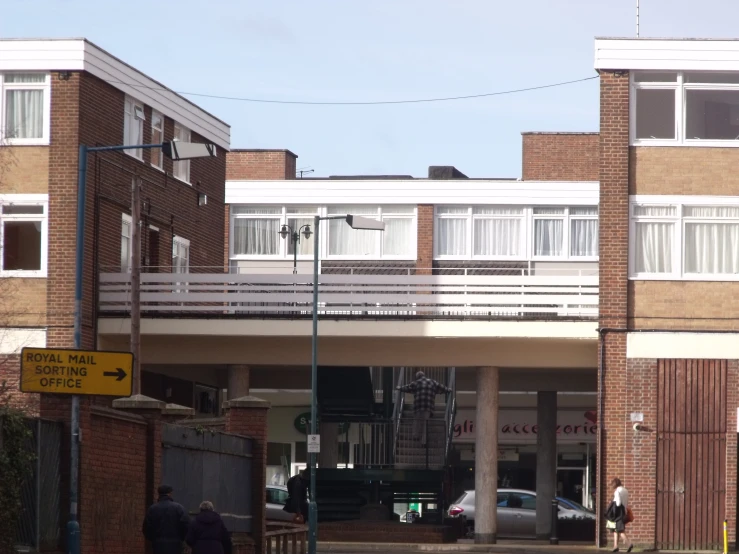 a group of people walking under an overpass next to a brick building