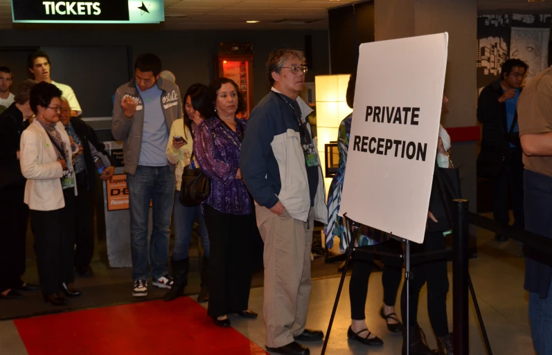 people standing in line next to a sign with a private reception written on it