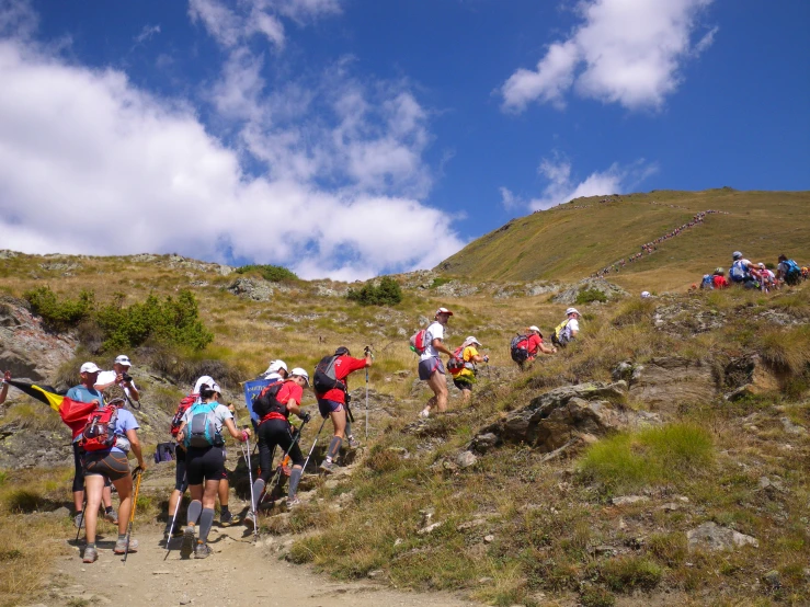 several people climbing up a steep slope to get to the top of a hill