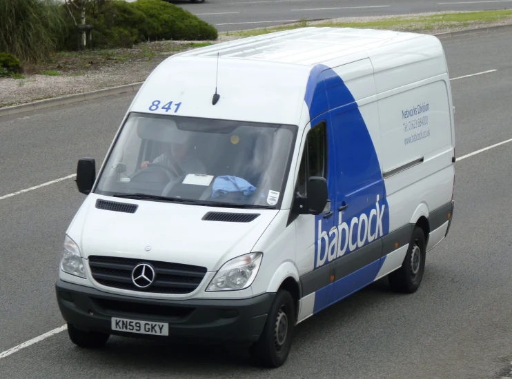 a white van driving down the road with people behind it