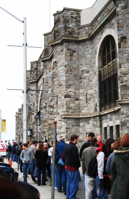 a crowd of people standing in front of a stone building