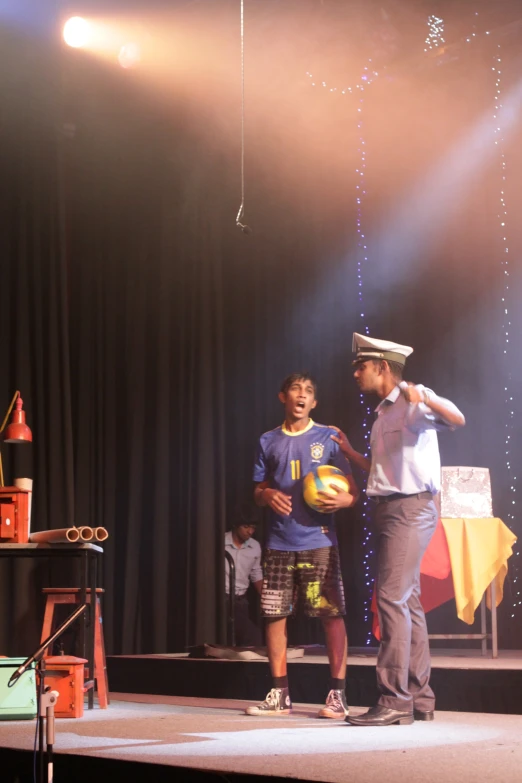 a man holding a ball talks to a  on stage