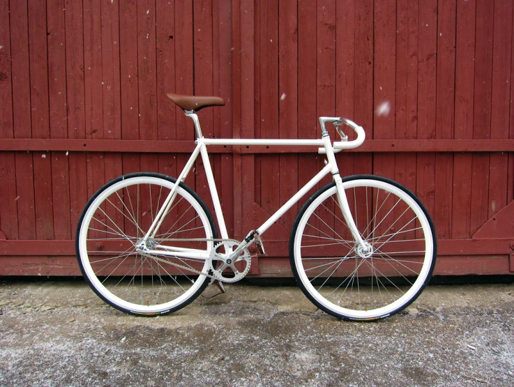 a bicycle leans against a barn door near it