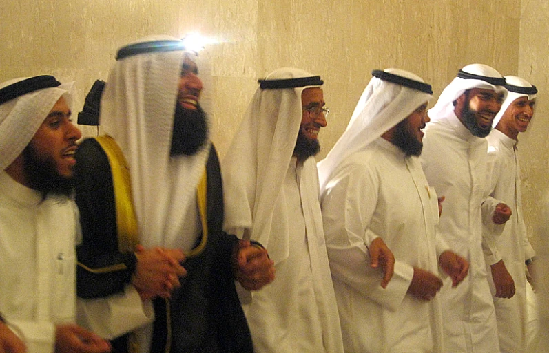 seven men in traditional white attire and long black hair