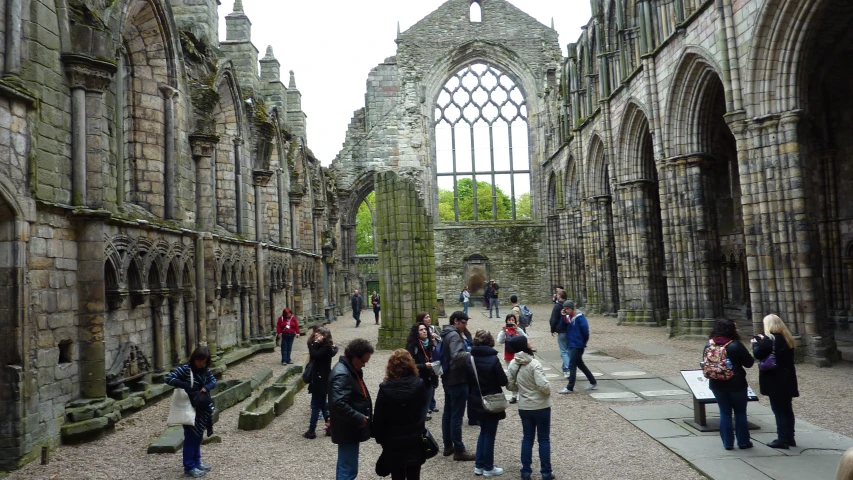 tourists are visiting a historic stone building with an old church window