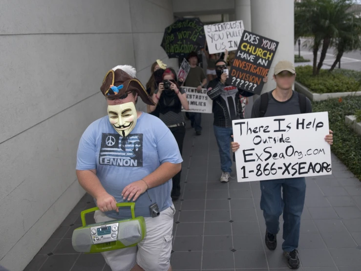 two people holding signs on the street with painted faces