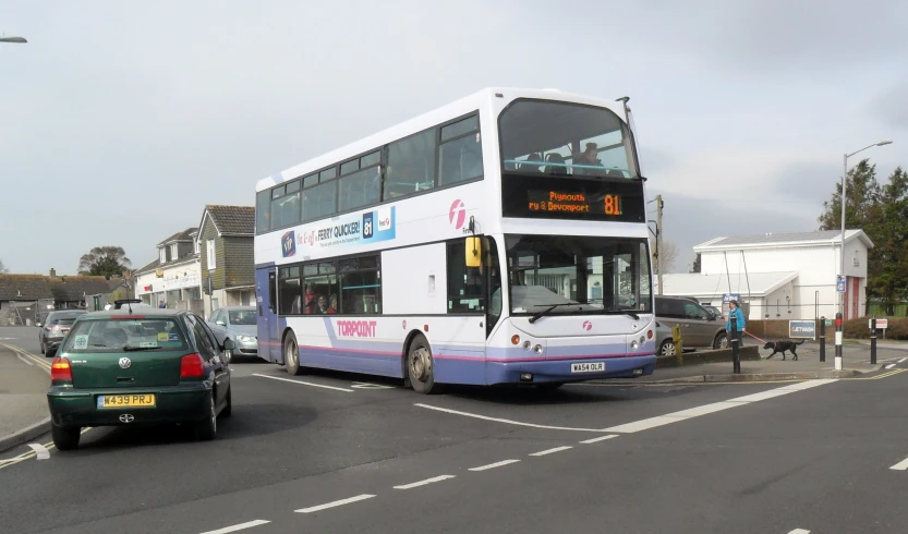 a white double decker bus driving down a street