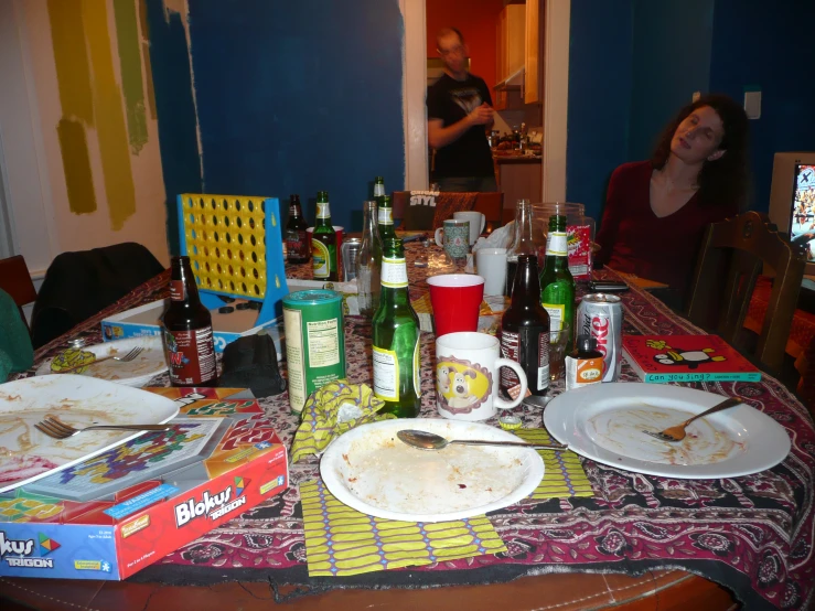 a dinner table with beer bottles, a plate and pizza