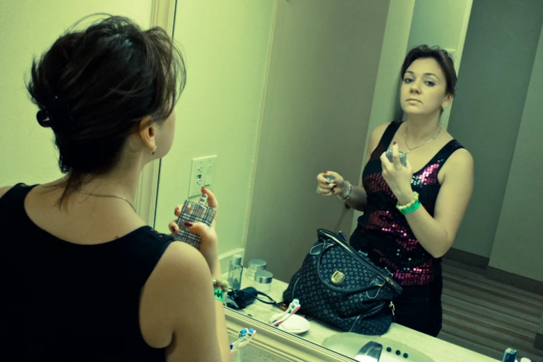 a woman with a purse looking at her reflection in a mirror