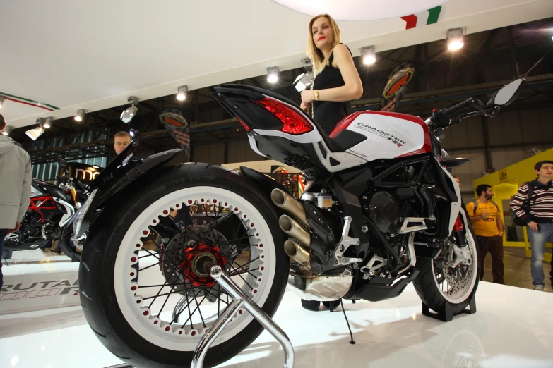 a woman standing next to a motorcycle on display