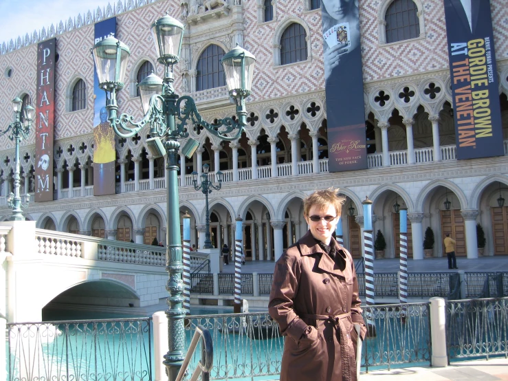 a woman poses in front of a building with large windows