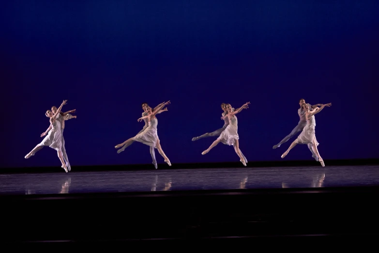 a row of ballet dancers, dancing on stage with dark background