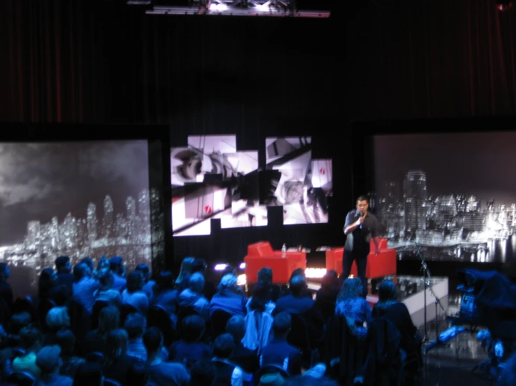 a man on stage giving a presentation to a large audience