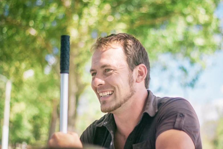 a man smiling while holding a metal detector