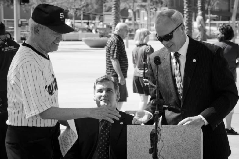 a man is speaking to a gentleman at an event