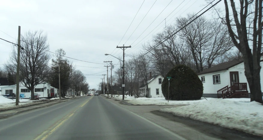 snow covers the street and houses along this side