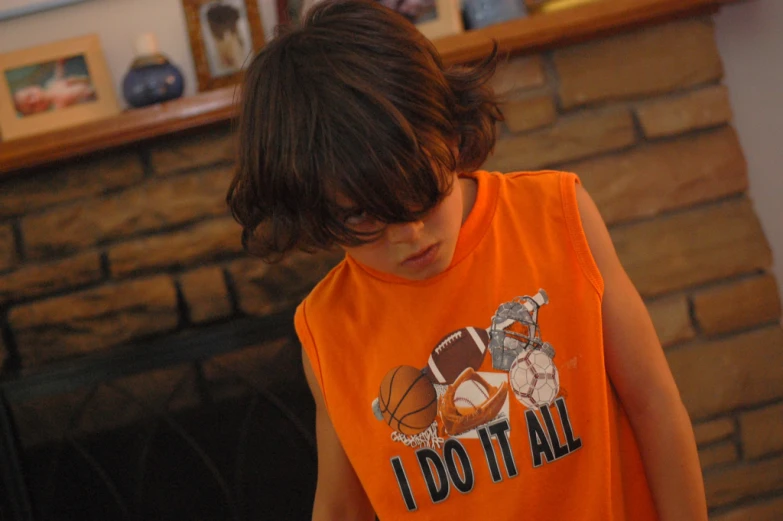 a boy wearing an orange basketball shirt is looking down