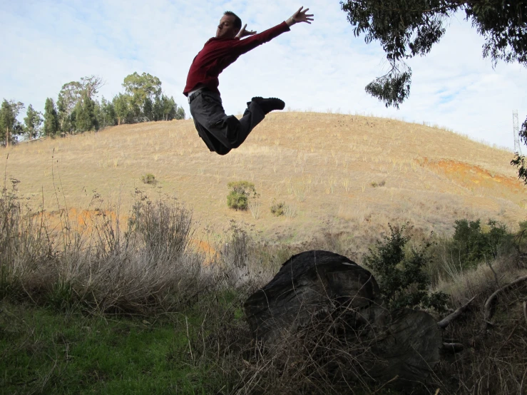 man jumping over a grassy hillside in the air